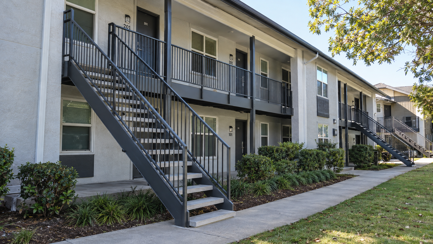 Exterior metal staircases with concrete treads and railings at an apartment building.