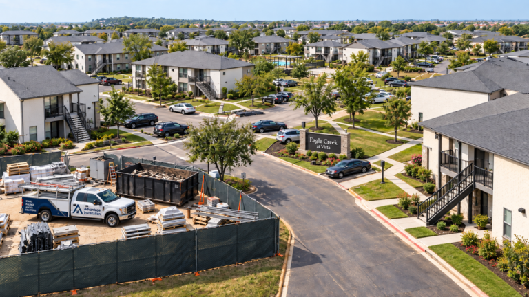 Apartment community with a fenced repair staging area, work truck, and construction materials.